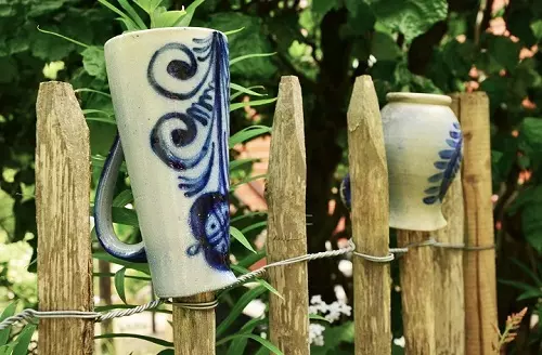 Umgedrehte Tontöpfe auf Staketenzaun.